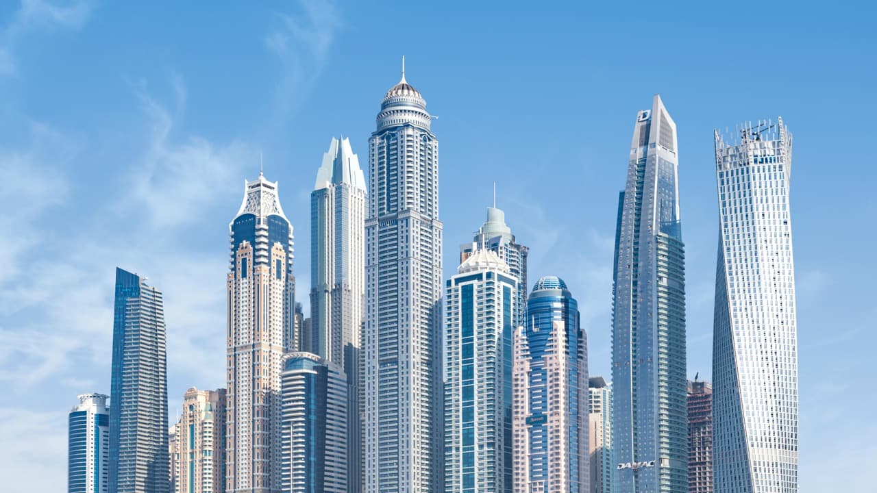 Skyline of modern skyscrapers against a clear blue sky, showcasing a variety of tall buildings with unique architectural designs.